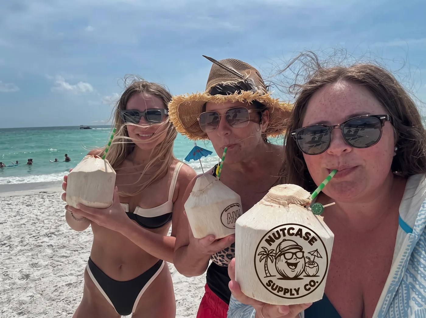 Three friends sipping coconuts on the beach